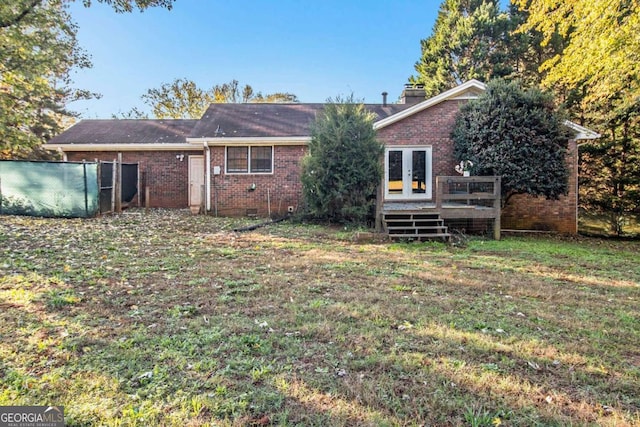 back of house featuring a yard, a wooden deck, and french doors