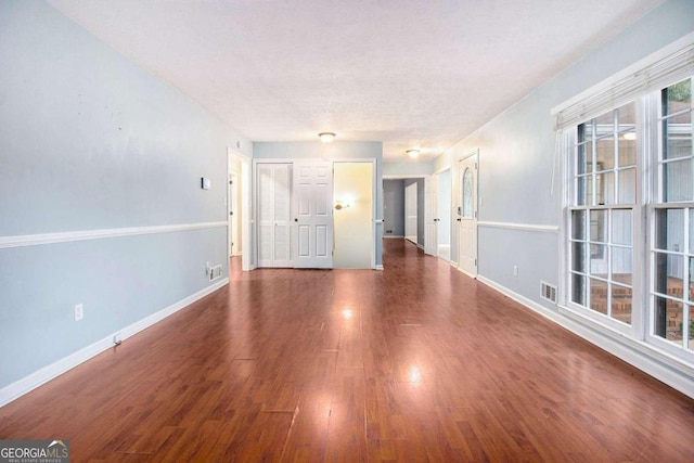 empty room with a textured ceiling and dark wood-type flooring