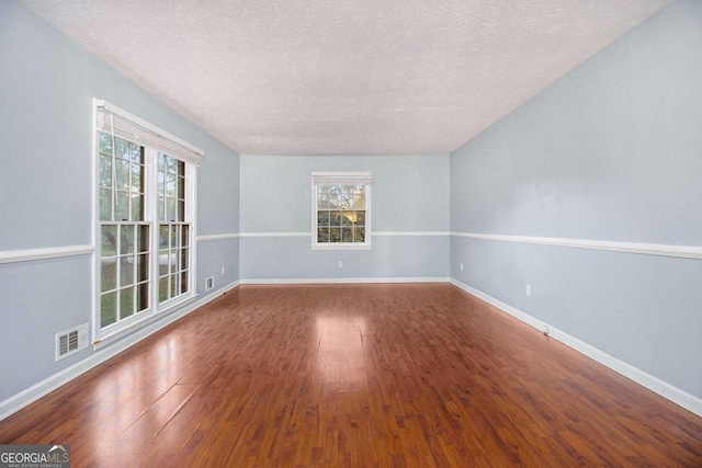 empty room with hardwood / wood-style flooring, a textured ceiling, and a wealth of natural light