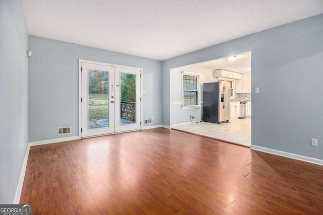 unfurnished living room featuring hardwood / wood-style floors and french doors