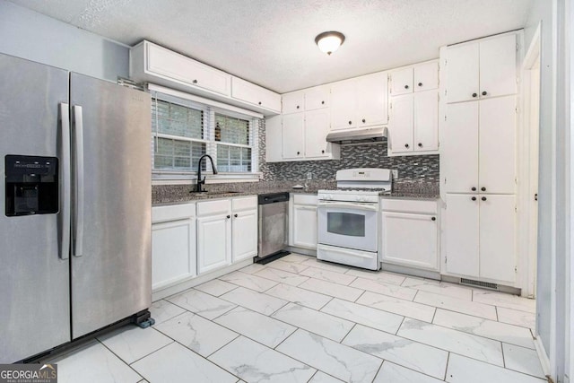 kitchen featuring decorative backsplash, a textured ceiling, stainless steel appliances, sink, and white cabinets