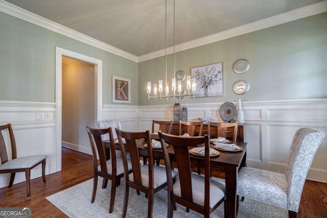 dining space with dark hardwood / wood-style flooring, ornamental molding, and an inviting chandelier