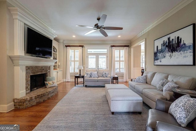 living room featuring a brick fireplace, ornamental molding, ceiling fan, hardwood / wood-style flooring, and built in features