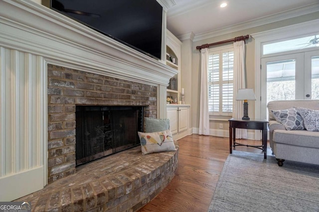 living area featuring ceiling fan, ornamental molding, dark hardwood / wood-style floors, and a brick fireplace