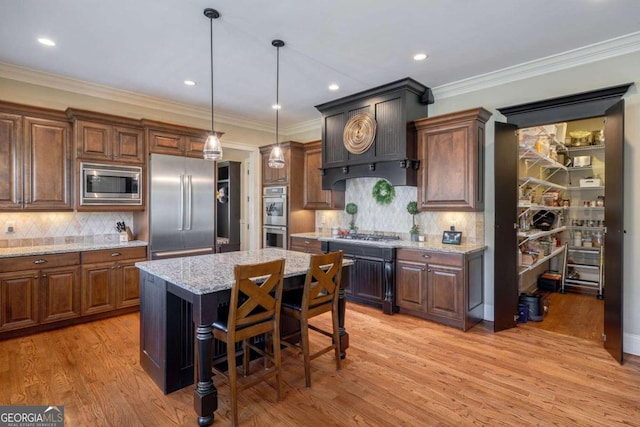 kitchen with decorative backsplash, appliances with stainless steel finishes, a center island, and light hardwood / wood-style floors