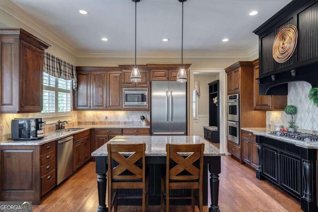 kitchen with pendant lighting, a center island, decorative backsplash, light wood-type flooring, and appliances with stainless steel finishes