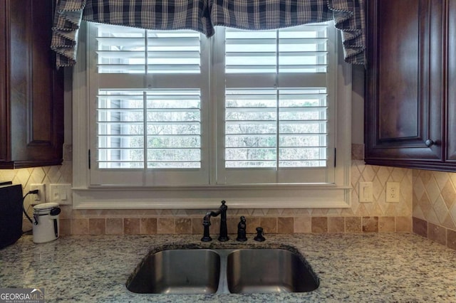 room details featuring decorative backsplash, light stone countertops, and sink