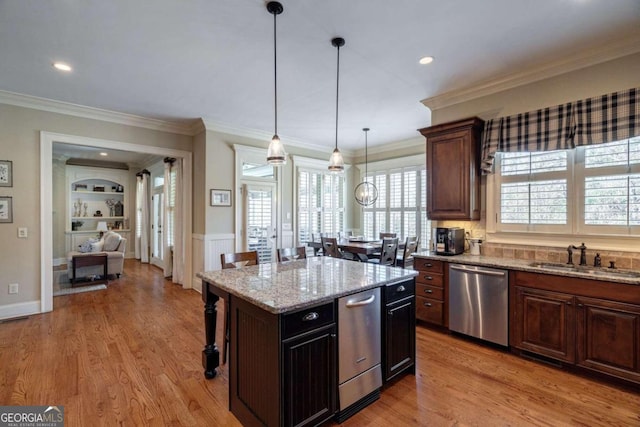 kitchen featuring a center island, sink, stainless steel dishwasher, light wood-type flooring, and a kitchen bar