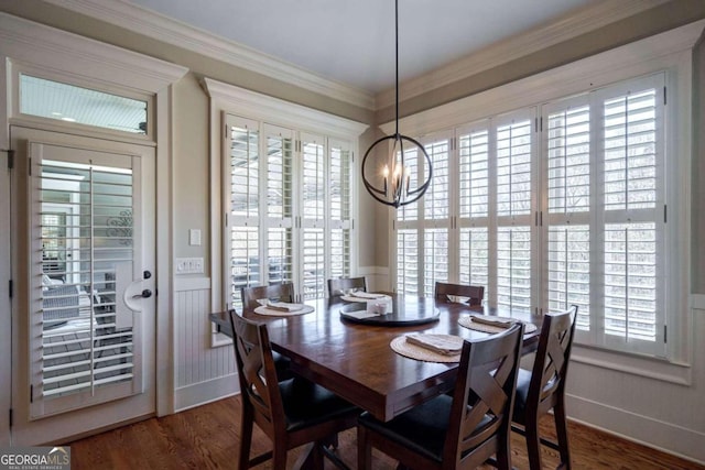 dining space featuring crown molding, dark wood-type flooring, a healthy amount of sunlight, and an inviting chandelier