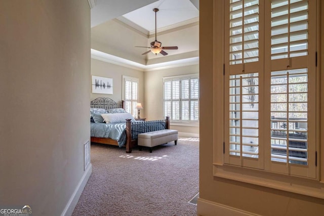 bedroom with carpet flooring, ceiling fan, ornamental molding, and a tray ceiling