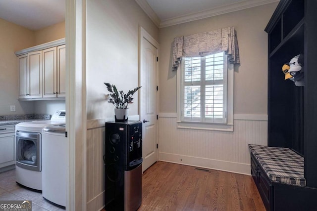 laundry room with washer and dryer, light hardwood / wood-style floors, crown molding, and cabinets