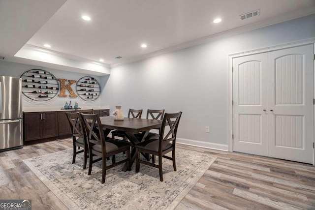 dining room with light hardwood / wood-style floors and crown molding