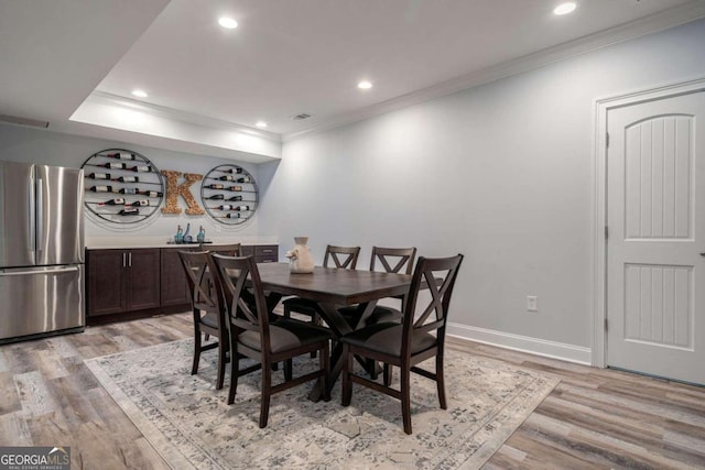 dining room with crown molding and light hardwood / wood-style flooring