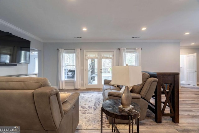 living room with french doors, light hardwood / wood-style flooring, ornamental molding, and a healthy amount of sunlight