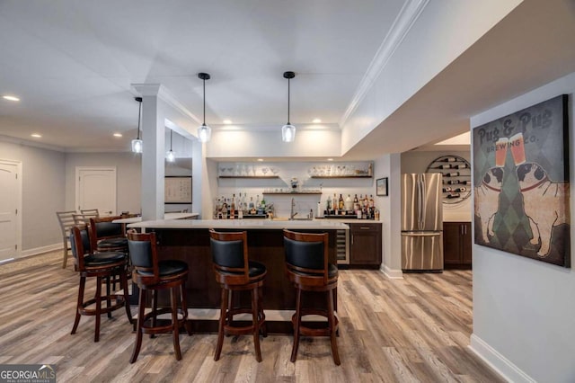 bar with stainless steel fridge, light hardwood / wood-style floors, hanging light fixtures, and ornamental molding