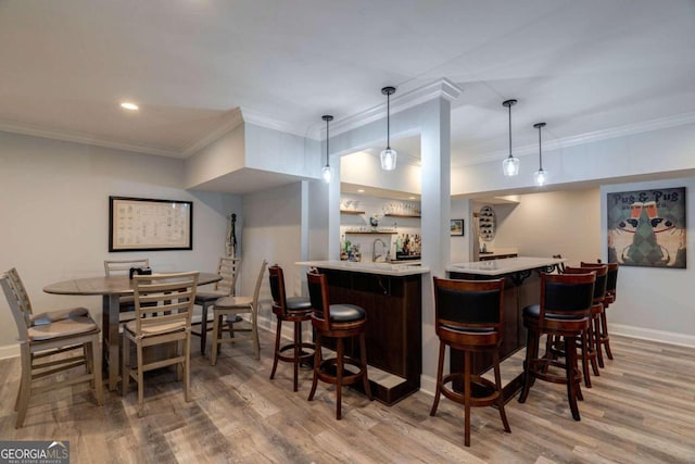 bar featuring wood-type flooring, hanging light fixtures, and crown molding