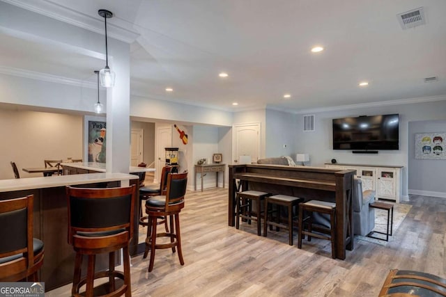 bar with decorative light fixtures, light hardwood / wood-style floors, and crown molding