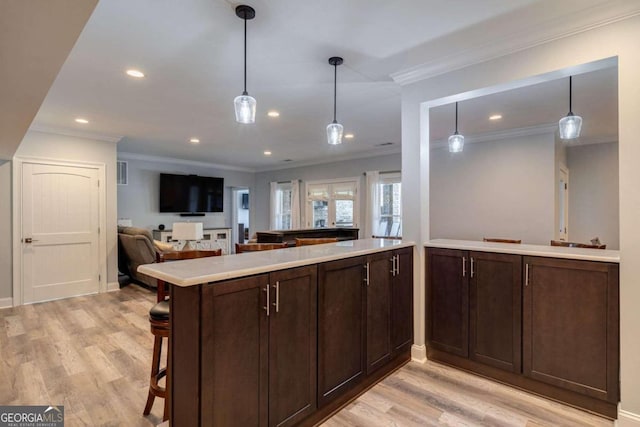 kitchen featuring a kitchen breakfast bar, kitchen peninsula, crown molding, pendant lighting, and light wood-type flooring