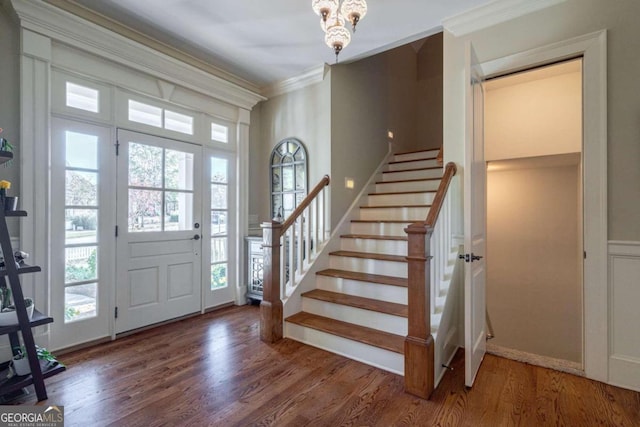 foyer featuring dark hardwood / wood-style flooring, ornamental molding, and a chandelier