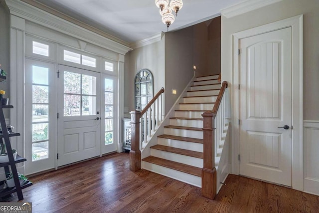 foyer featuring dark hardwood / wood-style flooring, ornamental molding, and a notable chandelier