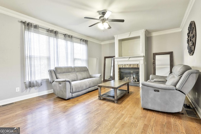 living room featuring ceiling fan, a fireplace, crown molding, and hardwood / wood-style flooring