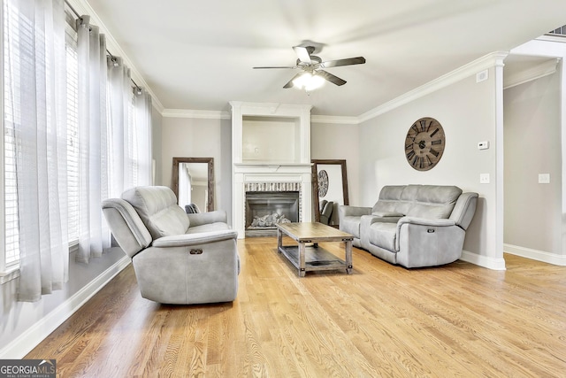 living room with a fireplace, ceiling fan, light hardwood / wood-style flooring, and ornamental molding