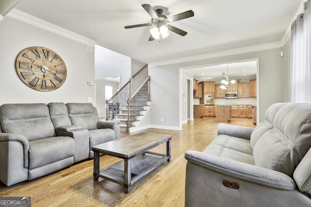 living room featuring ceiling fan with notable chandelier, light hardwood / wood-style flooring, and crown molding