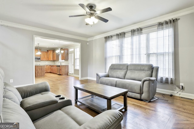 living room with ceiling fan, ornamental molding, and light hardwood / wood-style flooring