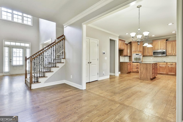 kitchen featuring an inviting chandelier, light wood-type flooring, appliances with stainless steel finishes, decorative light fixtures, and a kitchen island