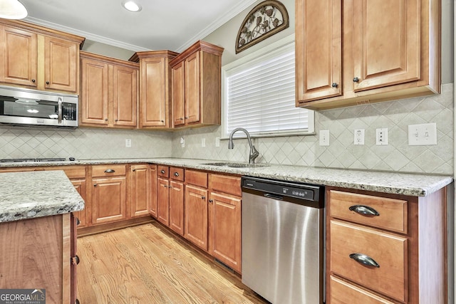 kitchen featuring light stone countertops, appliances with stainless steel finishes, light wood-type flooring, crown molding, and sink