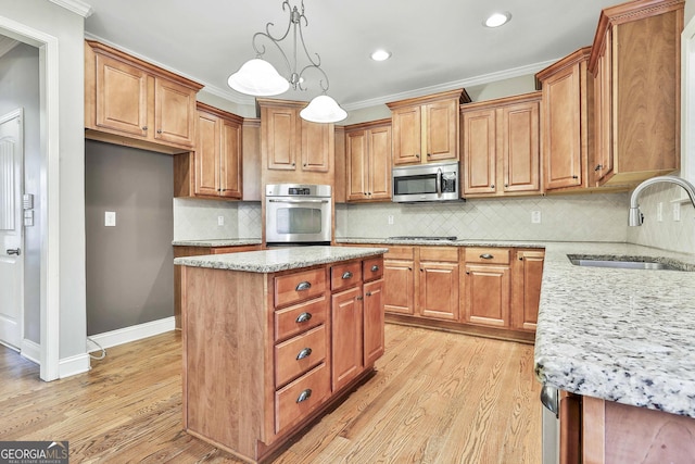 kitchen with backsplash, stainless steel appliances, sink, a center island, and light hardwood / wood-style floors