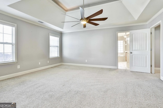 carpeted spare room with a tray ceiling, crown molding, and ceiling fan