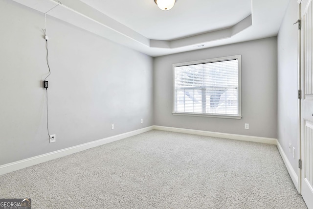 unfurnished room with a tray ceiling and carpet floors