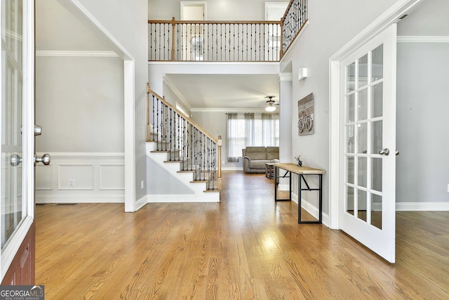 foyer entrance with french doors, light hardwood / wood-style flooring, ceiling fan, and ornamental molding