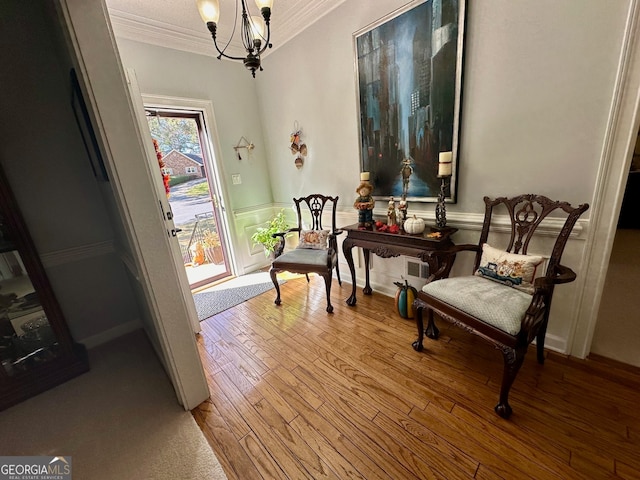 living area with a chandelier, light hardwood / wood-style flooring, and crown molding