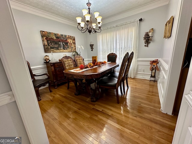 dining area featuring wood-type flooring, crown molding, and an inviting chandelier