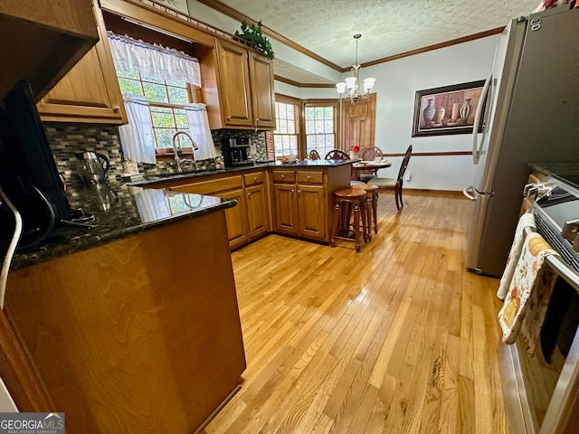 kitchen with pendant lighting, decorative backsplash, kitchen peninsula, and a textured ceiling