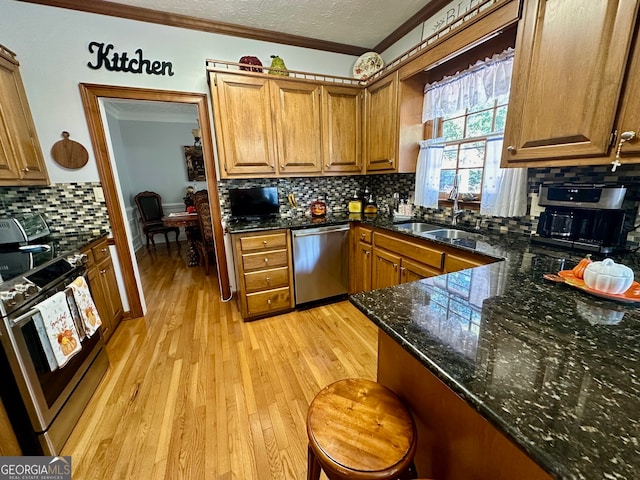 kitchen with sink, light hardwood / wood-style flooring, ornamental molding, tasteful backsplash, and stainless steel appliances