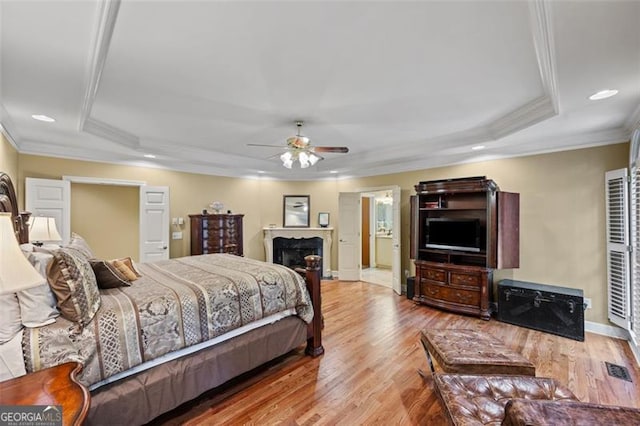 bedroom featuring a raised ceiling, ceiling fan, ornamental molding, and hardwood / wood-style flooring