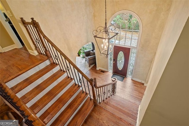 entryway featuring a towering ceiling, hardwood / wood-style flooring, and an inviting chandelier