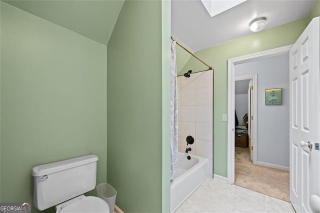 bathroom with vaulted ceiling with skylight, shower / bath combo, toilet, and tile patterned floors