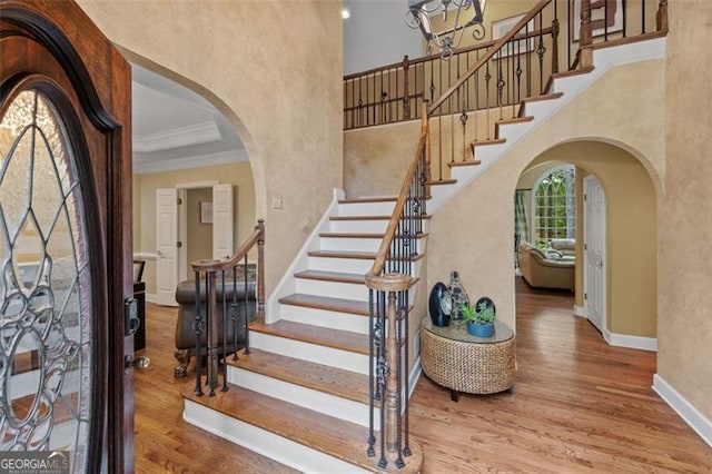 foyer featuring wood-type flooring, crown molding, and a tray ceiling