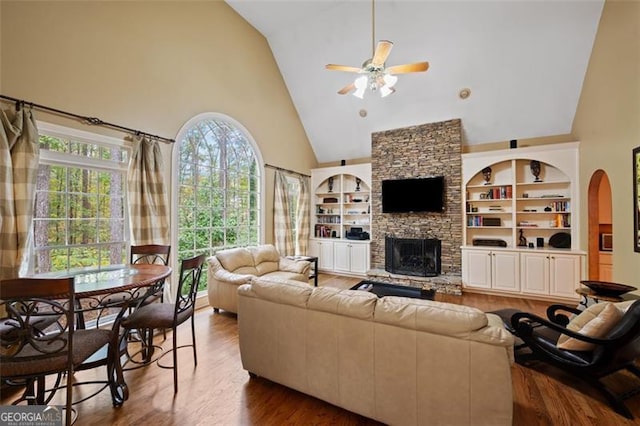 living room with a fireplace, dark hardwood / wood-style floors, high vaulted ceiling, and ceiling fan