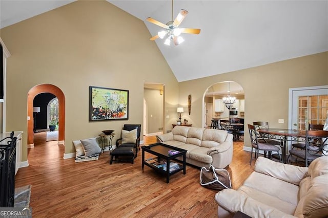 living room featuring hardwood / wood-style floors, ceiling fan with notable chandelier, and high vaulted ceiling