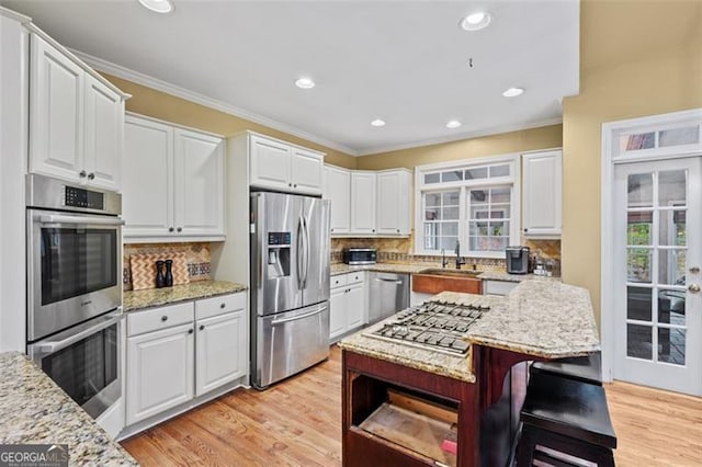 kitchen featuring stainless steel appliances, white cabinetry, tasteful backsplash, and light stone counters