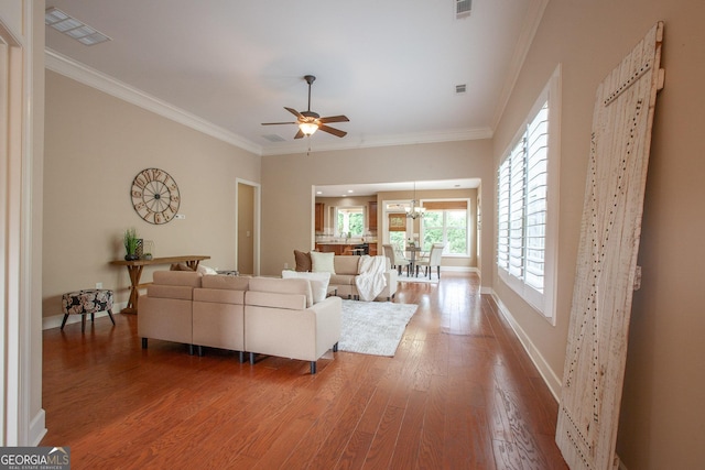 living room featuring visible vents, ceiling fan with notable chandelier, wood finished floors, and ornamental molding