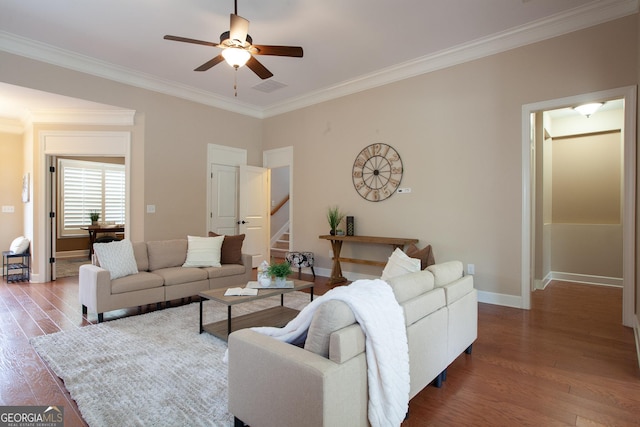 living area featuring stairway, wood finished floors, baseboards, ornamental molding, and ceiling fan