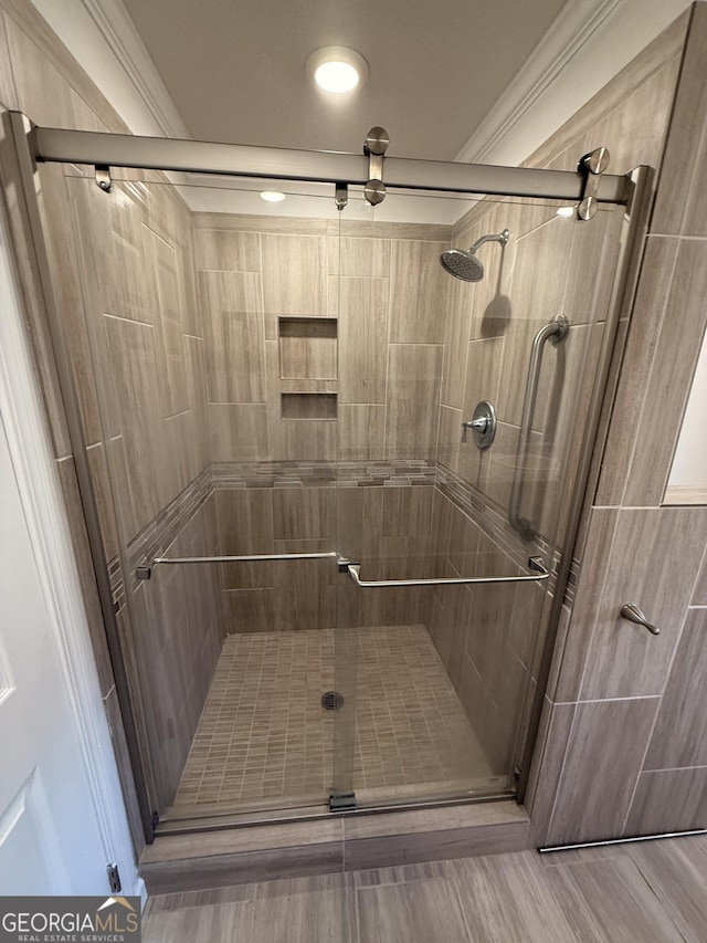 bathroom featuring hardwood / wood-style floors, ornamental molding, and a shower with door