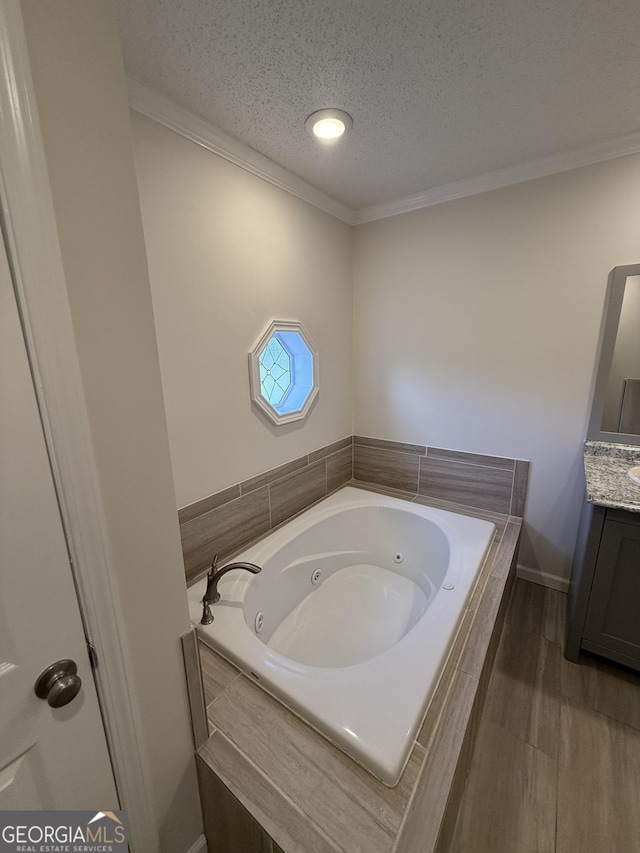 bathroom featuring a textured ceiling, vanity, crown molding, wood-type flooring, and tiled bath