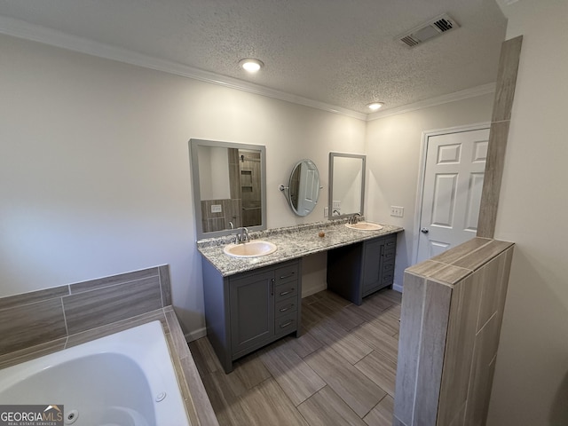 bathroom with vanity, a textured ceiling, a bathing tub, and ornamental molding